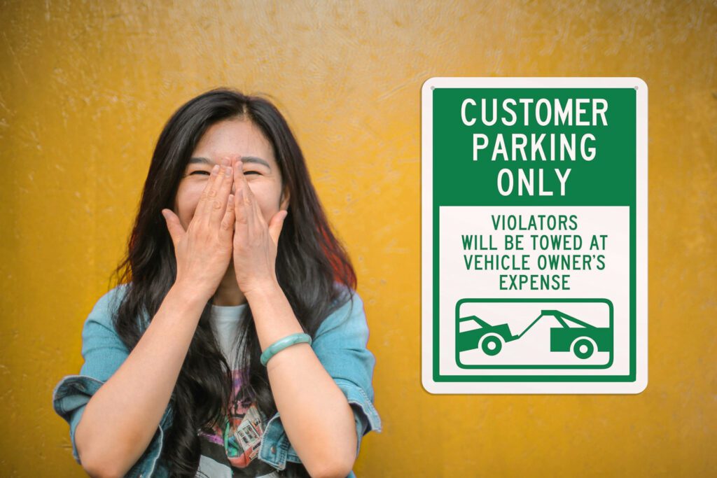 Woman laughing next a "Customer Parking Only" sign
