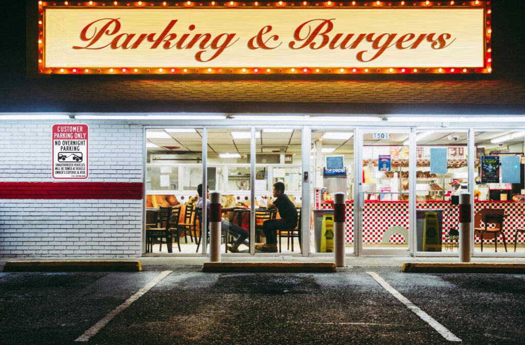 A burger restaurant facade with a "Customer Parking Only" sign